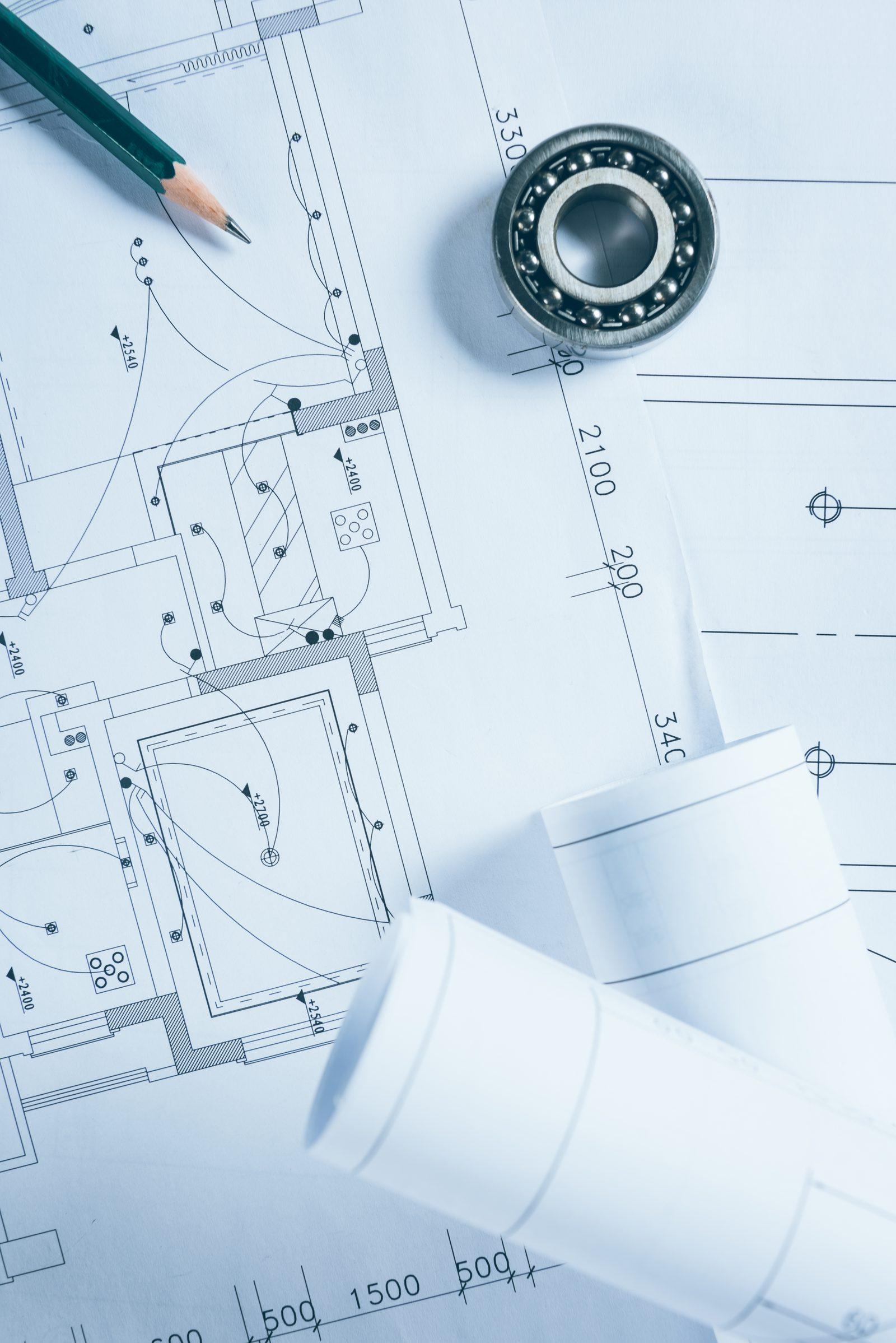 Floor plan drawing with a mechanical bearing part and rolled drawing sheets, in blue-toned lighting