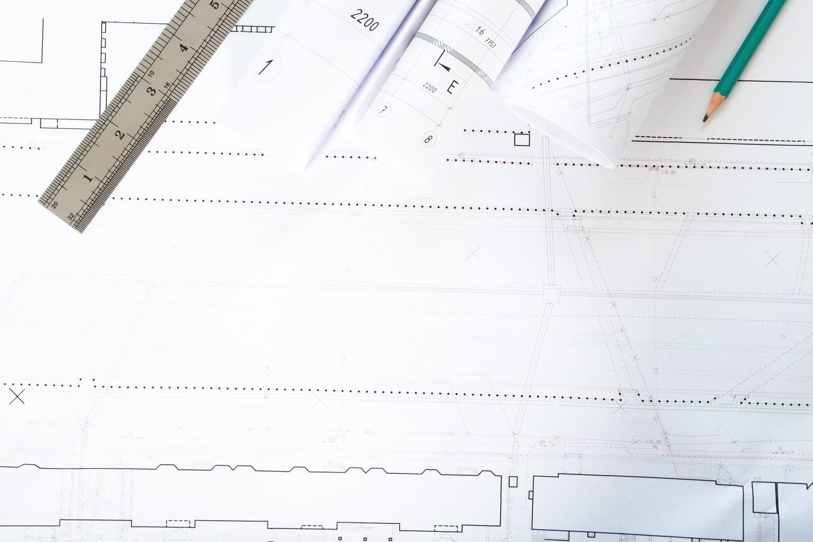 Ruler, rolled drawing sheets and a pencil on a blueprint page