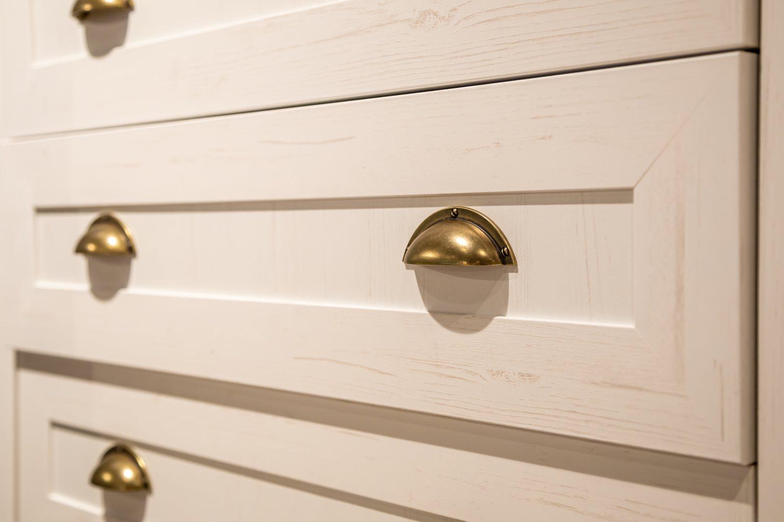 Close-up of brass cup pulls set into wood drawer fronts