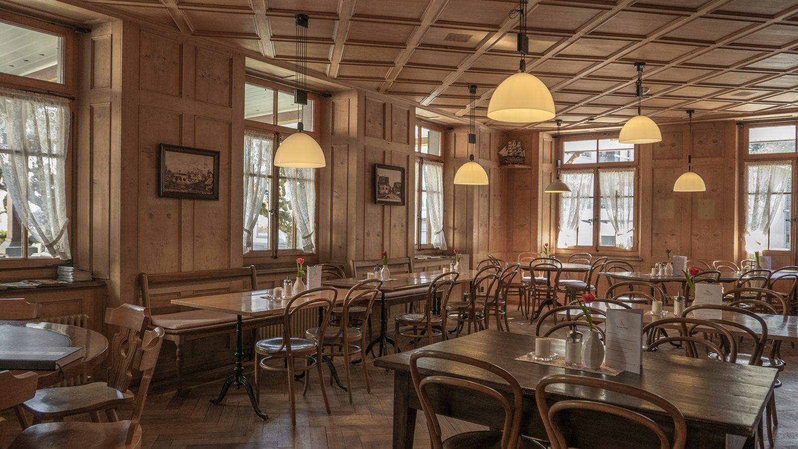 Restaurant dining room with wood tables, chairs and pendant lighting