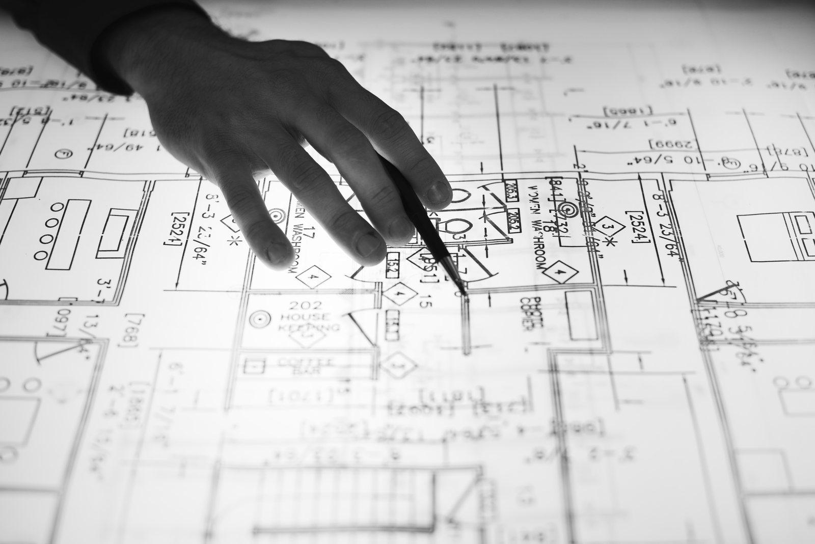 Hand pointing a pencil at a floor plan showing washroom and room labels